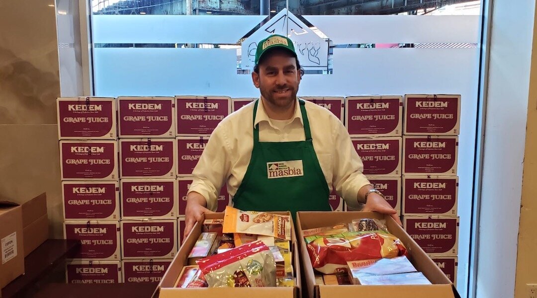 Masbia kosher supervisor Pesach Gittleson assembles boxes containing food for people who may be quarantined or unable to obtain food due to the coronavirus outbreak. (Alexander Rapaport)