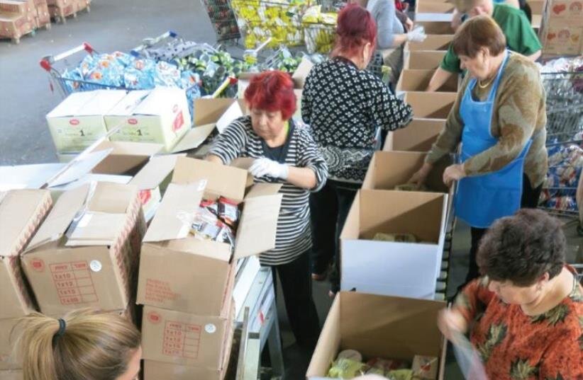 VOLUNTEERS PREPARE food packages for the needy ahead of Passover at a Kolel Chabad center earlier this week %image_alt%-9(photo credit: KOLEL CHABAD)