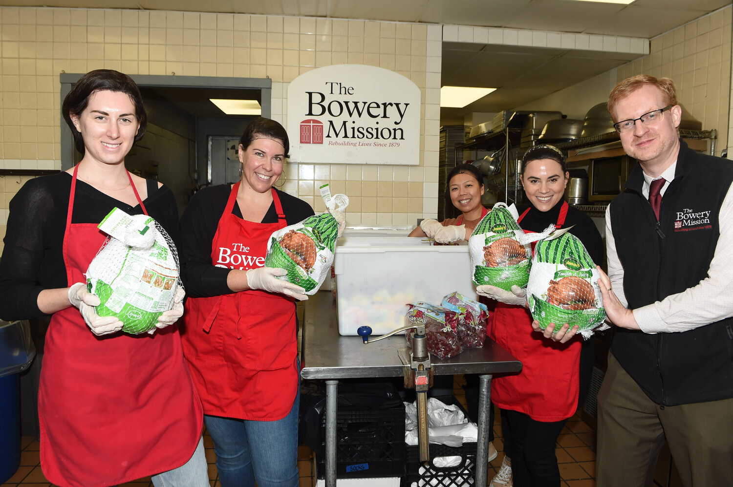 Members of the Bowery Mission prepare food, including special turkey dinners during Thanksgiving from City Harvest. They are (l-r) Volunteers Jennifer Libert, Natalie Nash, Cherie Tjhan, and Carlie Baker with Chief Development Officer James Winans. …