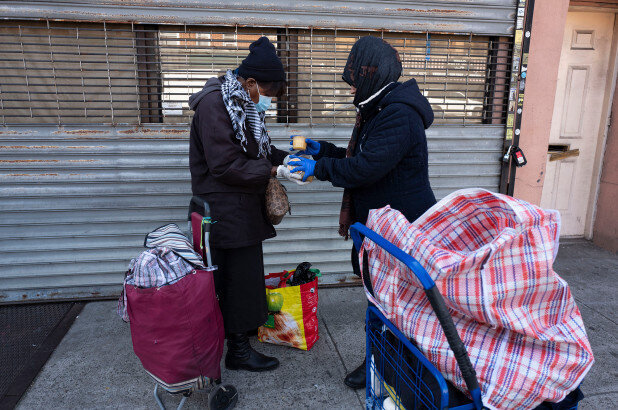 A woman, left, shares some of the food she picked up at Masbia Soup Kitchen with a woman who was unable to get food there during the coronavirus pandemic.