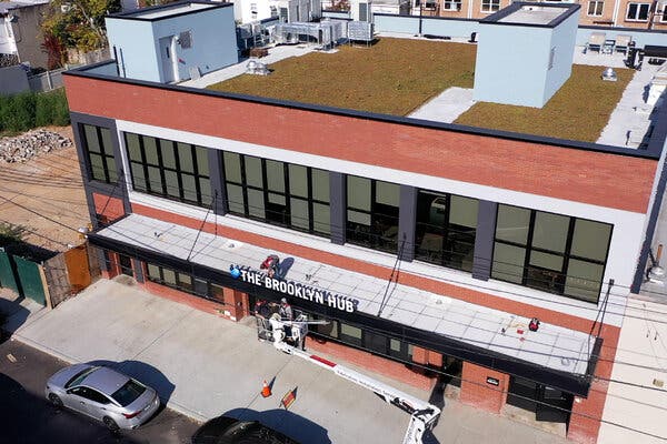 A view from a high angle of a brick building on a city street with a sign that reads “The Brooklyn Hub.”